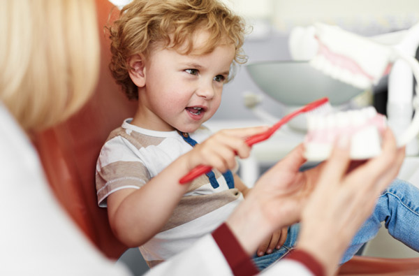 Little boy learning to brush teeth in our Houston, TX dentist office