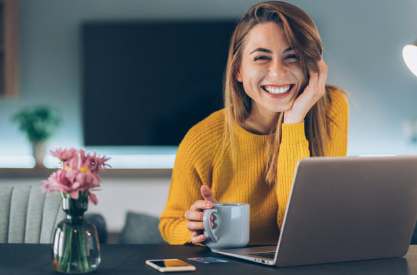 Woman smiling at desk with laptop in our Houston dental office.