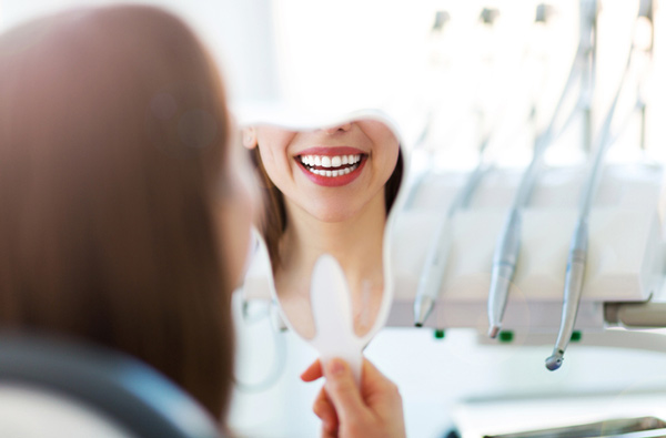 Woman looking at her smile in a mirror at our Houston dental office.